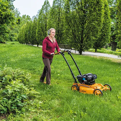 Frau mit Hörschutz mäht den Rasen mit einem Rasenmäher von AS Motor
